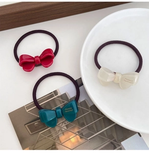 Detail of handmade acetate bow hair ties in burgundy, teal, and cream colors