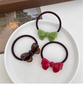 Three-piece set of handmade acetate bow hair ties in green, red, and tortoiseshell