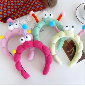Detail of colorful plush headbands with cartoon eyes and spiral antennas on white background