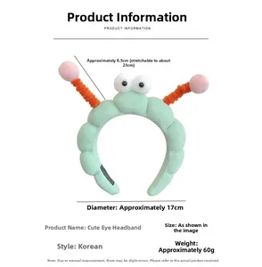 Detail view of plush green headband with cartoon big eyes and orange spring antennae