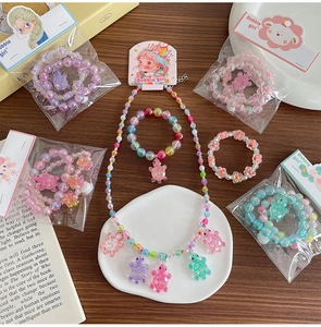Détail d'un ensemble collier et bracelets en perles colorées avec breloques tortue pailletées