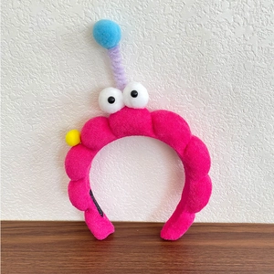 Close-up of rose red plush headband with big eyes and purple spring antenna detail