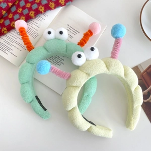 Cute plush cartoon headbands in mint green and pale yellow with funny big eyes