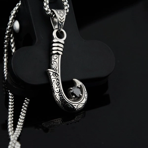 Macro shot of scythe-shaped pendant with black zircon in vintage stainless steel