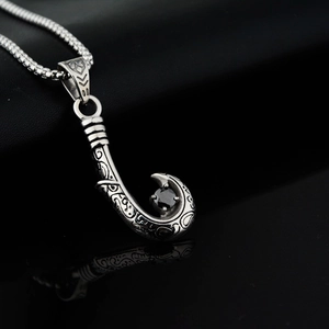 Detail of tribal totem fish hook pendant with a round black stone and box chain