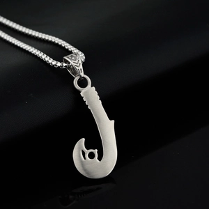 Close-up of brushed stainless steel fish hook pendant with Maori tribal engraving on chain