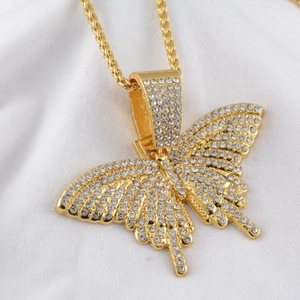 Vue macro du pendentif papillon doré serti de strass blancs scintillants et chaîne blé