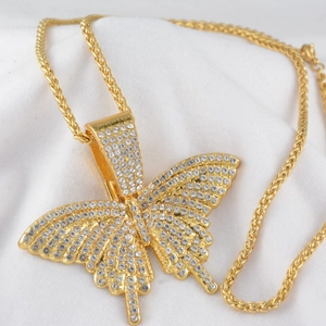 Collier hip hop avec pendentif papillon doré orné de strass sur fond de tissu blanc