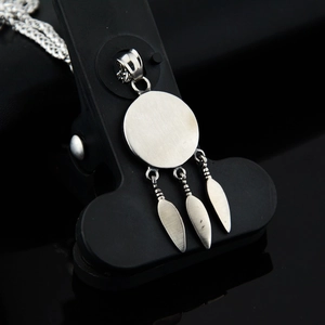 Silver stainless steel necklace with round pendant and three feathers on a black display
