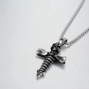 Détail d'un pendentif tête de mort et croix style punk sur une chaîne à mailles carrées