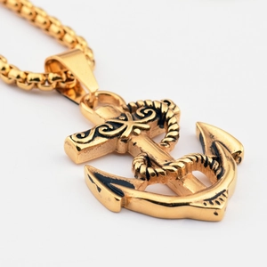 Close-up of golden anchor pendant with vintage wave patterns on a thick box chain