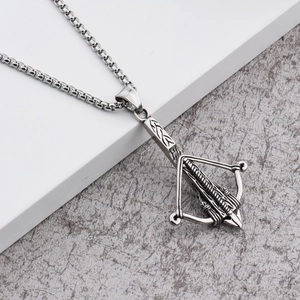 Détail du pendentif arbalète argenté vintage avec gravure et chaîne en perles