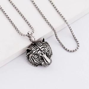 Detailed close-up of a vintage silver tiger head pendant with relief engraving