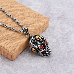 Détail d'un pendentif crâne punk vintage avec accents dorés et yeux en cristal rouge