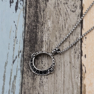 Dettaglio della collana vintage con incisione a rosa e gemme nere sul ciondolo ad anello