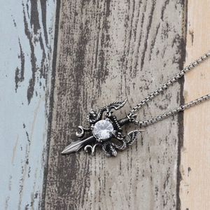 Macro shot of gothic sword dragon pendant with large crystal and steel chain detail