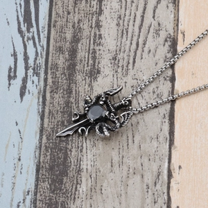 Macro detail of gothic dragon sword pendant with a black gemstone and steel box chain