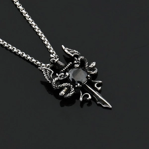 Macro shot of gothic sword pendant with dragon wings, black gemstone, and box chain