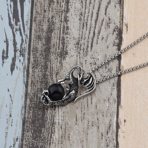 Vue détaillée du pendentif dragon vintage avec perle noire sur une chaîne maille vénitienne