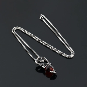 Détail du pendentif dragon en argent vieilli tenant une perle rouge sur chaîne box