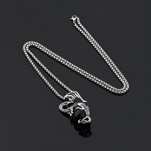Détail macro du pendentif dragon gothique tenant une perle noire sur chaîne en acier