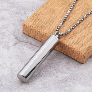 Collana con ciondolo a cilindro in acciaio al titanio argento su sfondo di marmo