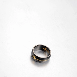 Vintage gunmetal stainless steel ring featuring gold cross patterns on grey background