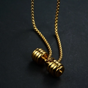 Macro shot of a golden dumbbell pendant on a round bead chain with metallic highlights