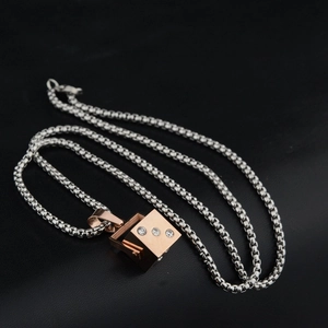 Macro detail of rose gold cube pendant with three zircons on silver box chain necklace