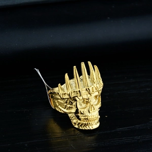 Macro shot of gold punk skull ring with spiked crown and vintage textured metal finish