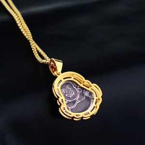 Detailed macro view of Buddha pendant with pink stone and golden snake chain