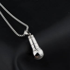 Polished silver microphone pendant necklace with box chain on a dark textured background
