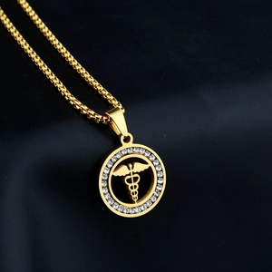 Collana con ciondolo caduceo medico dorato e strass su uno sfondo scuro testurizzato