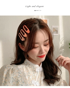 Close-up of a coral orange matte oval cutout hair clip worn on a model hair profile