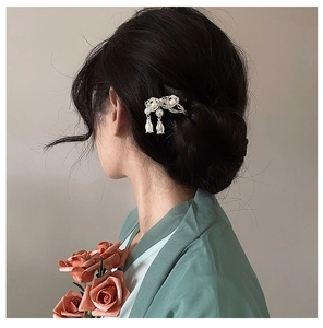 Detailed view of lily of the valley hair pin with pearl tassels on a sleek bun