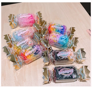Detail of candy-shaped packaging filled with colorful high-elastic hair bands on wood surface