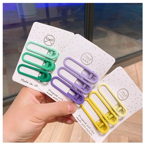 Close-up of matte alloy duckbill hair clips set in colorful gradient tones with packaging