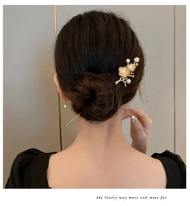 Detailed view of a gold plum blossom hair pin with white pearls on a model