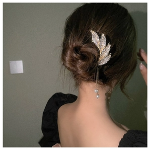 Detail of leaf hair pin with sparkling rhinestones and elegant pearl tassels on hair bun