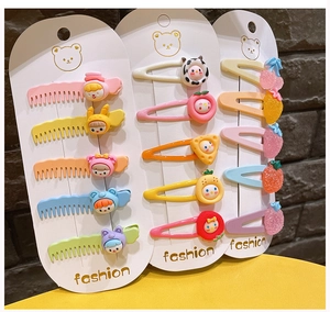 Detail of colorful children hair clips with cartoon fruit and comb designs on card