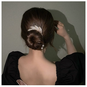 Detail of leaf hair pin with rhinestones and pearl tassels on a woman's hair bun