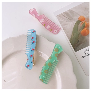 Detailed view of three acrylic floral hair clips in pink, light blue, and green colors
