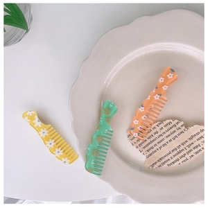 Close-up of portable small hair combs with floral patterns in yellow, green, and orange