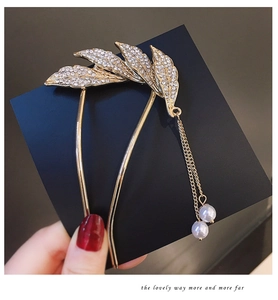 Detail of gold U-shaped hair pin featuring rhinestone leaves and pearl tassel charms