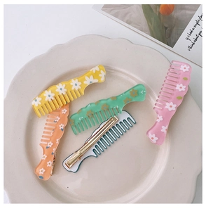 Close-up of daisy pattern comb-shaped acrylic hair clips in a ceramic bowl