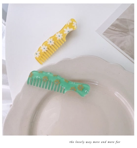 Close-up of decorative floral hair combs in yellow and mint green with daisy patterns