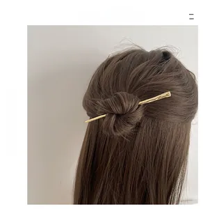 Close-up of golden hair stick with hammered metal texture in a hair bun styling