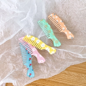 Cute comb-shaped floral hair clips in five colors on a textured white paper background