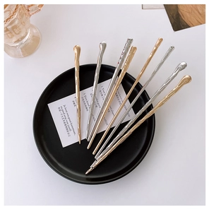 Close-up of textured gold and silver metal hair sticks with melted lava design and hole