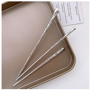 Detailed view of silver lava-textured hair sticks on a vintage metal tray set